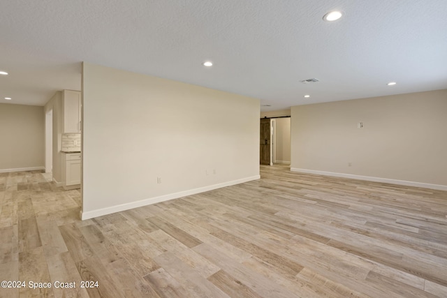 empty room with light wood-style floors, recessed lighting, and visible vents