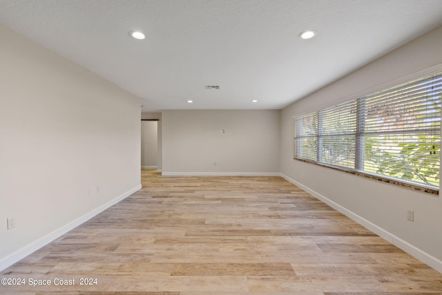 empty room featuring recessed lighting, light wood-type flooring, visible vents, and baseboards