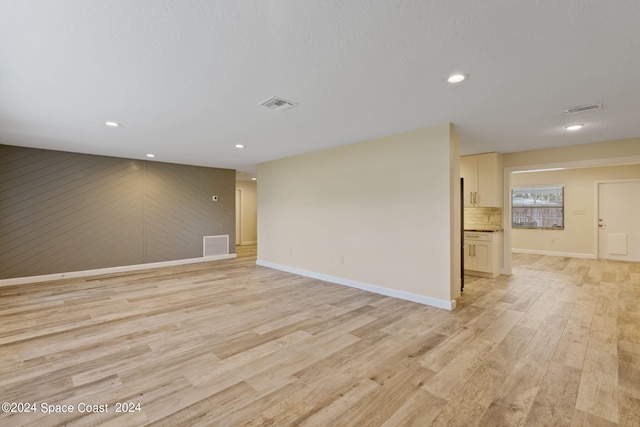 empty room featuring light wood-style floors, visible vents, and baseboards