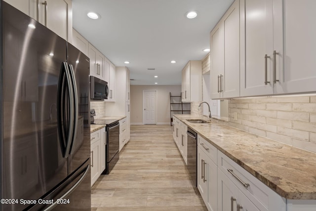 kitchen featuring black appliances, white cabinetry, and light stone counters