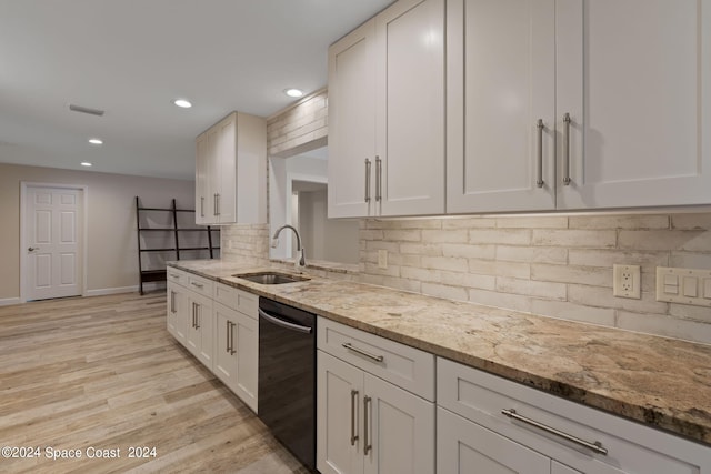 kitchen with light stone counters, a sink, white cabinetry, light wood-style floors, and black dishwasher