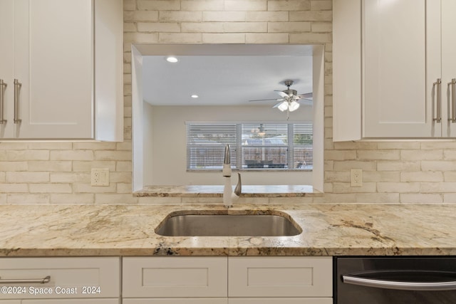 kitchen featuring a sink, a ceiling fan, white cabinets, light stone countertops, and dishwasher