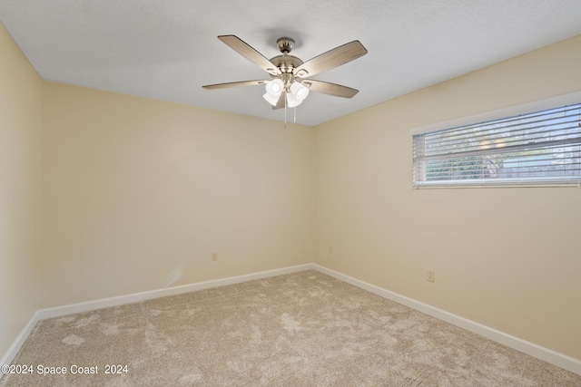 empty room featuring light colored carpet, ceiling fan, and baseboards