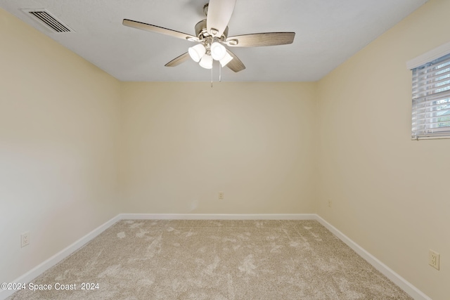 spare room with light carpet, a ceiling fan, visible vents, and baseboards