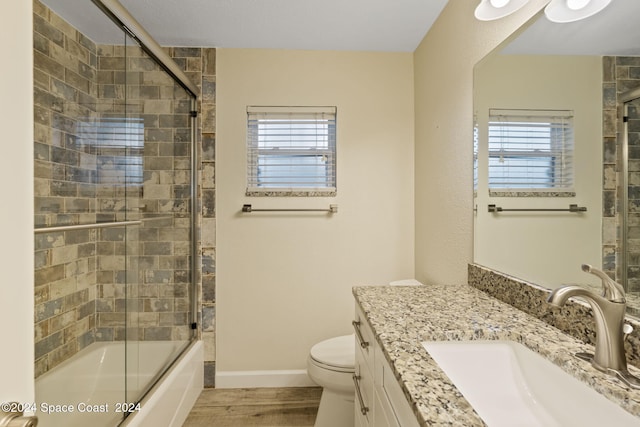 full bath with toilet, plenty of natural light, bath / shower combo with glass door, and vanity