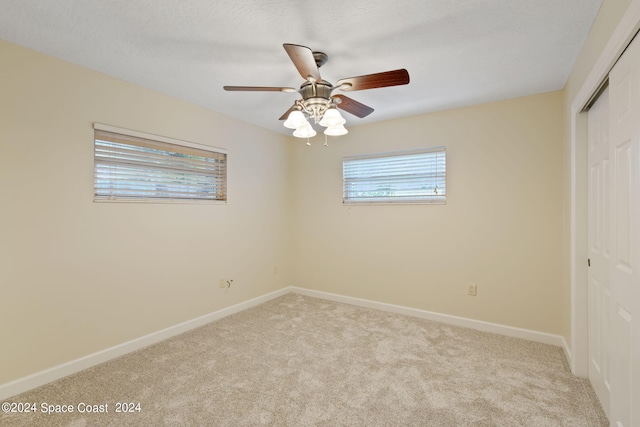 unfurnished bedroom featuring light carpet, ceiling fan, baseboards, and a closet