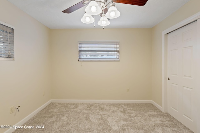 empty room with a ceiling fan, light carpet, and baseboards