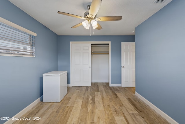 unfurnished bedroom with baseboards, a closet, light wood-style flooring, and refrigerator