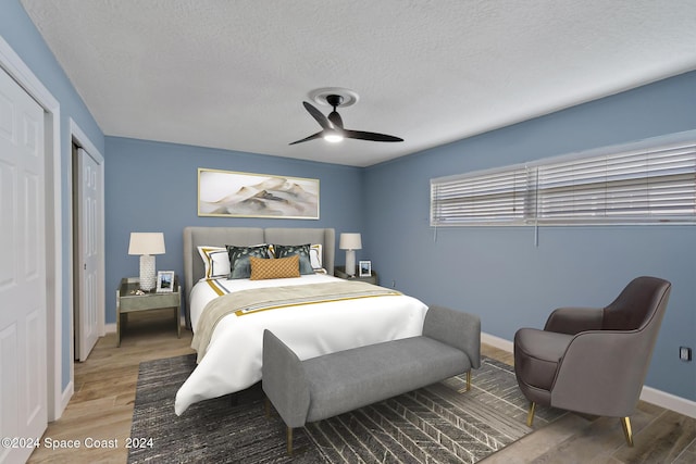 bedroom with a ceiling fan, a textured ceiling, baseboards, and wood finished floors