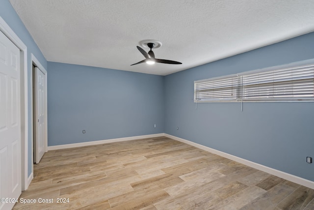 unfurnished bedroom featuring ceiling fan, light wood-style flooring, baseboards, and a textured ceiling