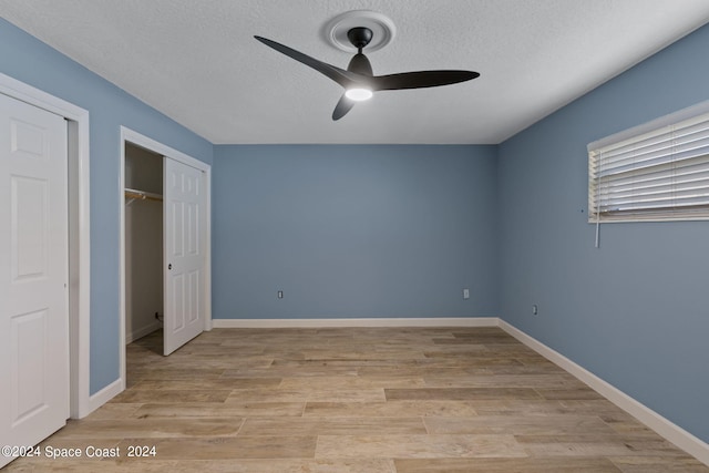 unfurnished bedroom with a textured ceiling, a ceiling fan, baseboards, a closet, and light wood-type flooring