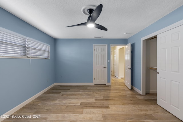 unfurnished bedroom with a textured ceiling, light wood finished floors, visible vents, and baseboards