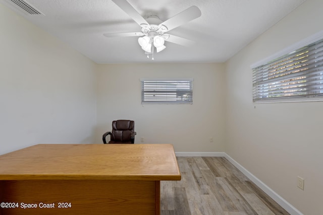 unfurnished office featuring ceiling fan, light wood finished floors, visible vents, and baseboards