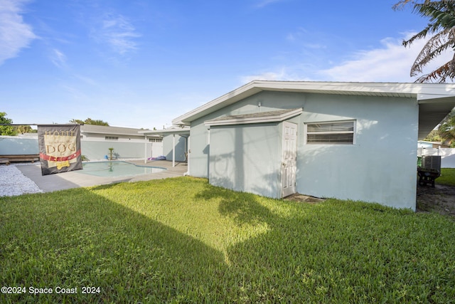 rear view of property featuring a lawn, a pool, and stucco siding