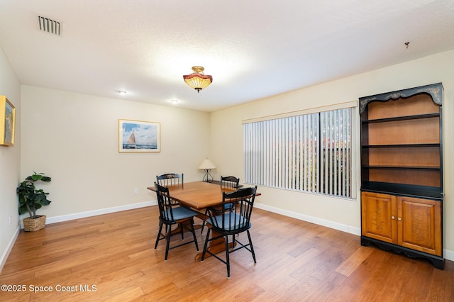 dining room featuring baseboards, visible vents, and light wood-style floors