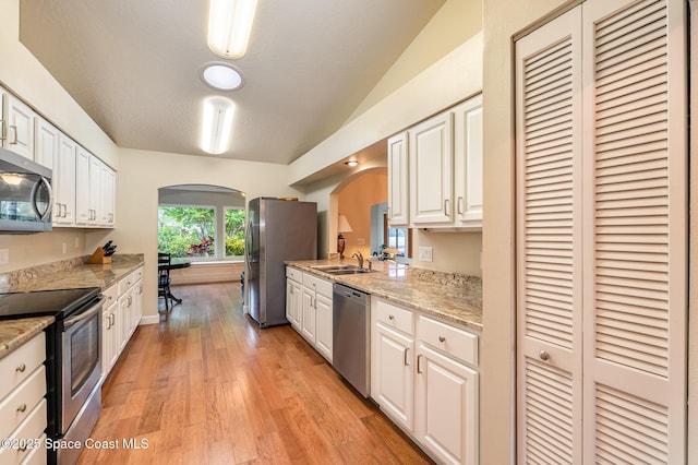 kitchen with white cabinetry, appliances with stainless steel finishes, arched walkways, and a sink