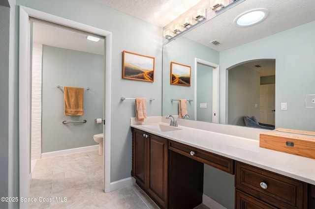 bathroom with baseboards, toilet, a textured ceiling, and vanity