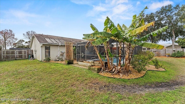 rear view of house featuring a yard and glass enclosure