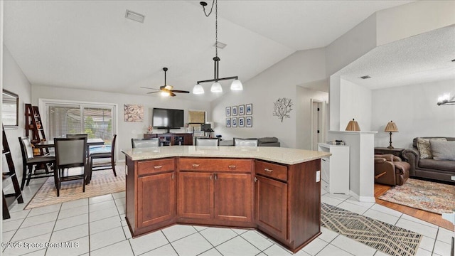 kitchen featuring light stone counters, vaulted ceiling, light tile patterned floors, a kitchen island, and pendant lighting