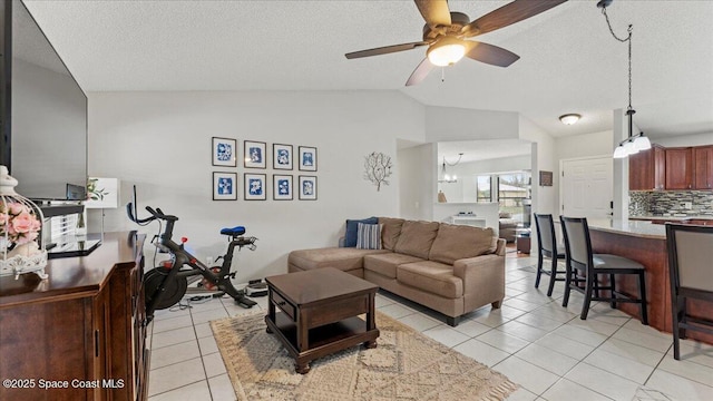 tiled living room featuring lofted ceiling, ceiling fan with notable chandelier, and a textured ceiling