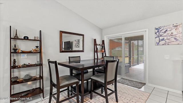 dining area with light tile patterned flooring, lofted ceiling, and a textured ceiling