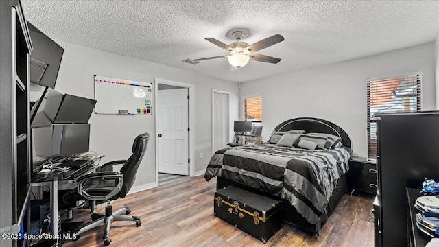 bedroom with hardwood / wood-style flooring, a textured ceiling, and ceiling fan