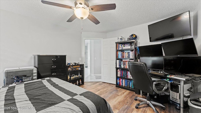 bedroom with wood-type flooring, a textured ceiling, and ceiling fan