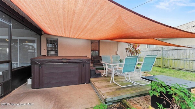 wooden deck featuring a hot tub and a patio