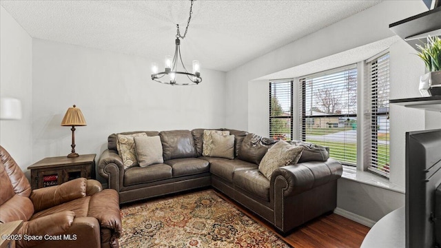 living room featuring dark wood-type flooring, a textured ceiling, and a notable chandelier