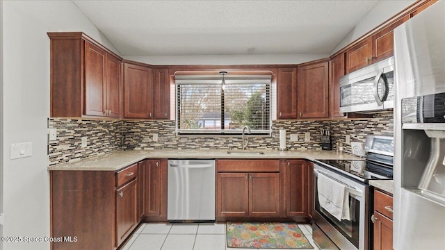 kitchen featuring tasteful backsplash, sink, light tile patterned floors, and appliances with stainless steel finishes