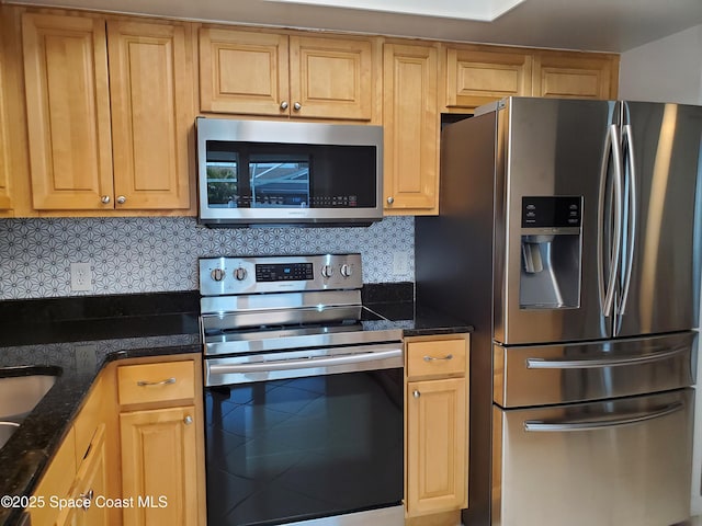 kitchen featuring stainless steel appliances, decorative backsplash, and dark stone countertops