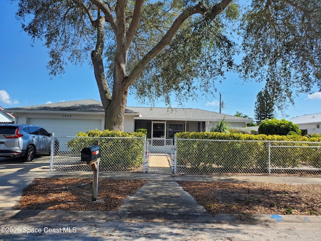 ranch-style house featuring driveway, a fenced front yard, an attached garage, and a gate