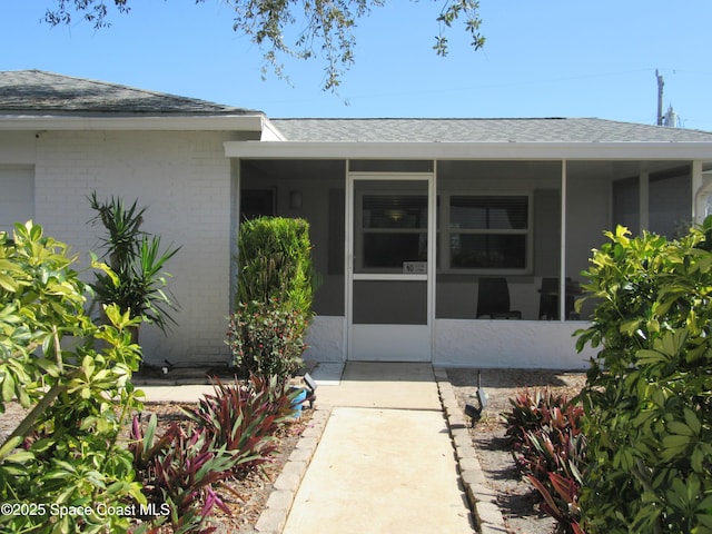 property entrance featuring brick siding and roof with shingles