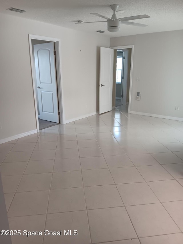 empty room with baseboards, tile patterned flooring, visible vents, and a textured ceiling