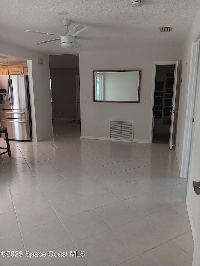 empty room with a ceiling fan, visible vents, and light tile patterned flooring