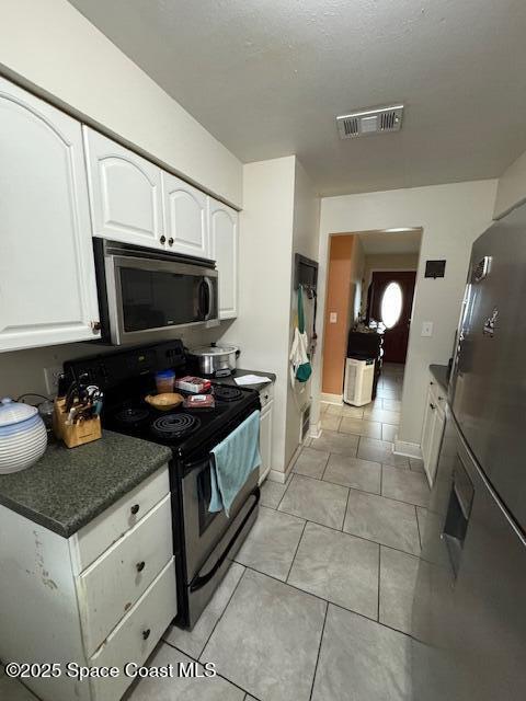 kitchen featuring white cabinetry, stainless steel appliances, and light tile patterned flooring