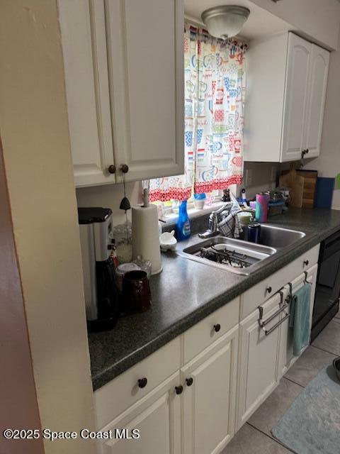 kitchen with sink, white cabinets, black dishwasher, and light tile patterned flooring