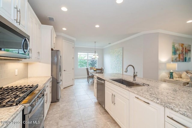 kitchen with pendant lighting, appliances with stainless steel finishes, sink, white cabinetry, and light stone countertops