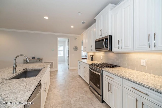 kitchen featuring light stone counters, white cabinets, appliances with stainless steel finishes, and sink