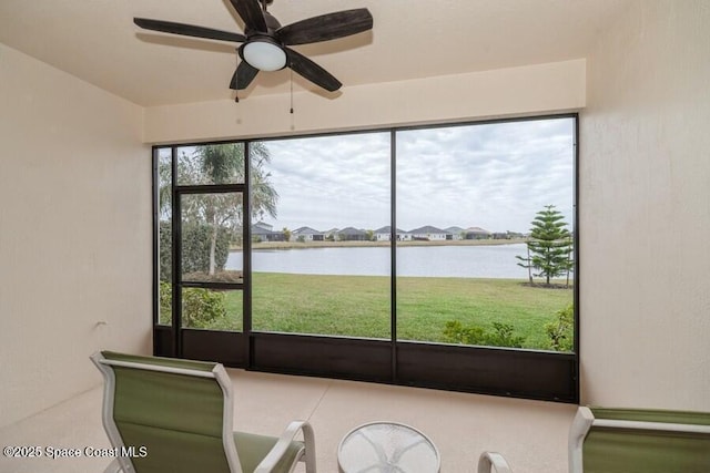 unfurnished sunroom with ceiling fan and a water view