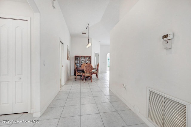 corridor with light tile patterned floors and lofted ceiling