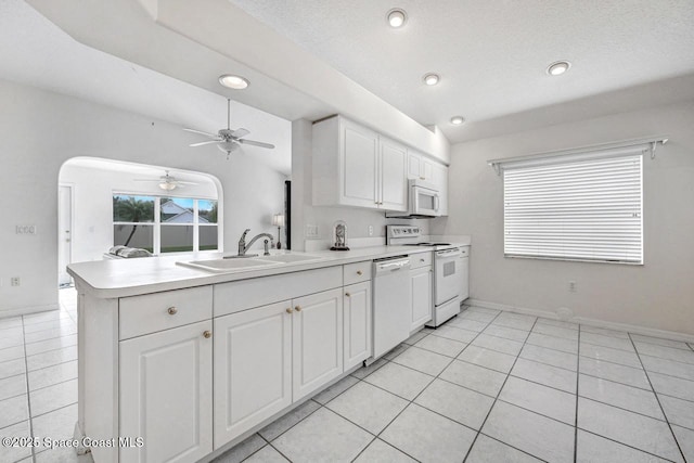 kitchen featuring sink, white appliances, white cabinetry, and kitchen peninsula