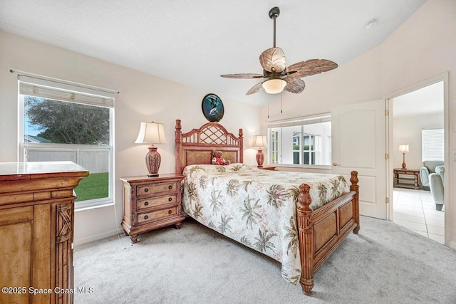 bedroom with ceiling fan, light colored carpet, and multiple windows