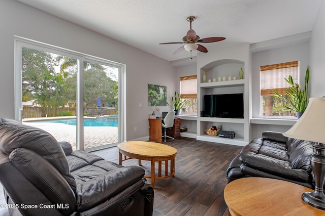 living room featuring dark wood-type flooring, ceiling fan, and a textured ceiling