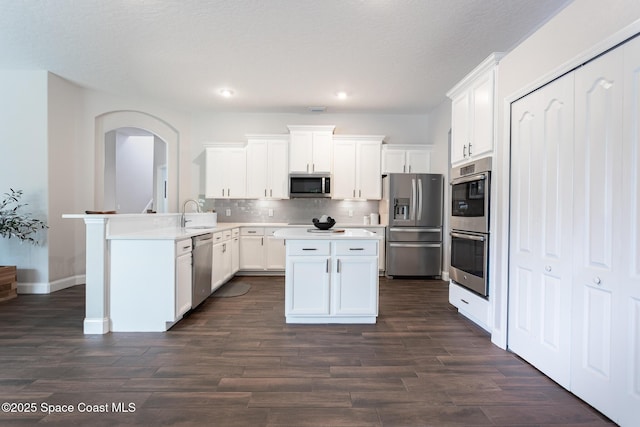 kitchen featuring stainless steel appliances, white cabinetry, tasteful backsplash, and kitchen peninsula