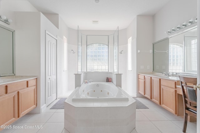 bathroom featuring vanity, a wealth of natural light, tile patterned floors, and tiled bath