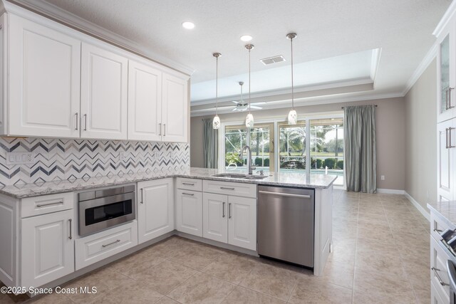 3489 Ahern Pl, Melbourne, FL 32940 - kitchen featuring a peninsula, visible vents, a raised ceiling, stainless steel appliances, and a sink