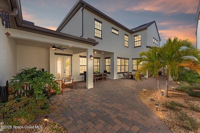 back house at dusk with a patio, french doors, and ceiling fan