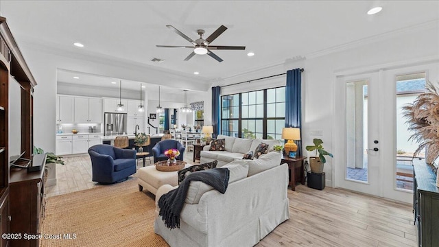 living room featuring visible vents, a ceiling fan, light wood-style flooring, ornamental molding, and recessed lighting