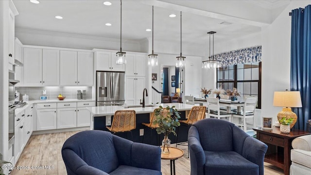 kitchen with open floor plan, light countertops, stainless steel refrigerator with ice dispenser, and crown molding